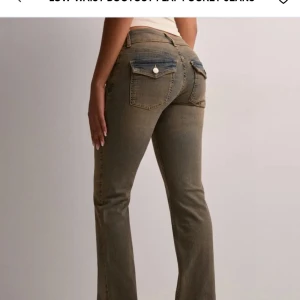 Bruna bootcut jeans med fickdetaljer - Snygga bruna bootcut jeans med låg midja och unika fickdetaljer. Perfekta för en avslappnad stil med en twist. De har en klassisk femficksdesign och en bekväm passform. Väldigt stretchiga