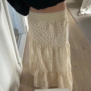 Beige långkjol med broderad spets - Säljer en vacker beige långkjol med broderad spets och volanger. Kjolen är aldrig använd!              Jag är 172!