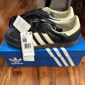 Adidas Samba OG sneakers - Helt nya oanvända Snygga Adidas Samba OG sneakers i svart och vit med klassiska tre ränder på sidan. Skorna har en gummisula med bra grepp och snörning för perfekt passform. Perfekta för en stilren look.