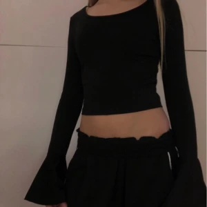 Svart croppad topp med vida ärmar - Snygg svart croppad topp med långa vida ärmar. Perfekt för en trendig look. Passar bra till både jeans och kjol.