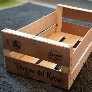 Trälåda med texten 'Virgen del Rocio' - Charmig trälåda med texten 'Virgen del Rocio' och logotypen 'Las Arenas finas'. Perfekt för förvaring eller som dekorativ detalj i hemmet. Lådan har en rustik känsla med naturligt trä och tryckt text. 