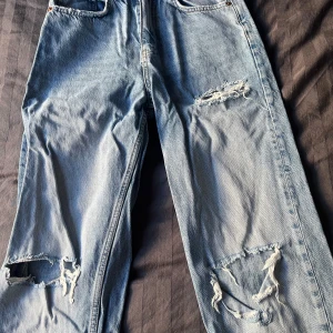 Ljusa jeans med slitningar från Gina tricot - Säljer ett par ljusa jeans från Gina tricot med slitningar på benen. Använda men i bra skick. Lite rakare i benslut med slitningar längst ner. 