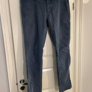 Grå byxor från NN07 - Snygga grå byxor från NN07 i modellen Simon. Tillverkade i en bomullsblandning med lite stretch för extra komfort. Perfekta för en stilren look med normal passform och klassisk design.