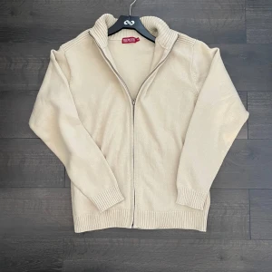 Stickad fullzip - Säljer en schysst beige stickad kofta från Redwood med dragkedja framtill. Koftan har långa ärmar och en ribbad krage samt muddar vid ärmslut och nederkant. Perfekt för kyligare dagar. Den är i väldigt bra skick och är i storlek M. Modellen är 180cm och väger 70kg. Det är bara att höra av sig vid övriga frågor eller funderingar!