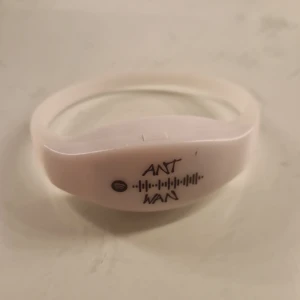 Vitt armband med tryck ant wan,lampan funkar inte men man kan byta batteri - Säljer ett vitt armband med tryck av texten 'ANT WAN' och en ljudvåg. Armbandet har en enkel och stilren design, perfekt för vardagsbruk eller som en unik accessoar.