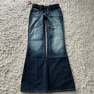 Blå bootcut jeans från Redial - Snygga blå bootcut jeans från Redial med en cool tvättad look. De har framfickor och bakfickor med dragkedja för extra stil. Perfekta för en avslappnad och trendig stil.