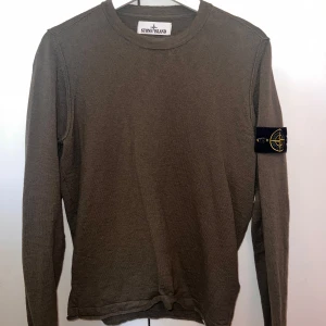 Grön tunn långärmad tröja från Stone Island - Säljer en stilren grön tunn långärmad tröja från Stone Island. Tröjan har en ikonisk logga på ärmen och är perfekt för en avslappnad look. Den är tillverkad i ett bekvämt material som passar bra till vår och sommar