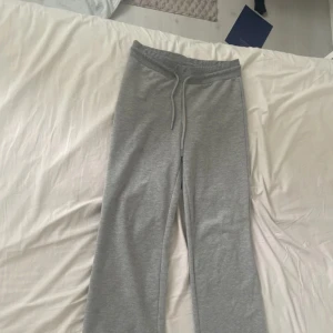 Grå mjukisbyxor med snörning - Bekväma grå mjukisbyxor med elastisk midja och snörning. Perfekta för en avslappnad dag hemma eller en snabb tur till affären. Byxorna har en rak passform och är tillverkade i mjukt material för extra komfort.