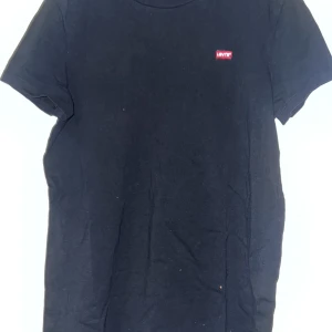 Svart t-shirt från Levi's - Säljer en klassisk svart t-shirt från Levi's med liten logga på bröstet. Perfekt för en stilren look. Tillverkad i mjukt material för extra komfort. Passar till det mesta och är ett måste i garderoben.