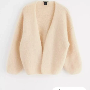 Beige kofta från Zara - Mysig beige kofta från Zara med en enkel och stilren design. Den har en öppen front och är tillverkad i ett mjukt material som ger en skön känsla. Perfekt för kyligare dagar.