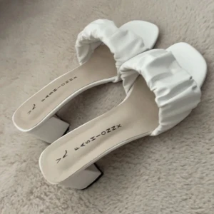 Vita klackskor  - Stilrena vita klackskor med bred rem i rynkat material💓💓Storlek 39 men passar 38