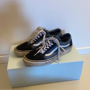 Svart och blå sneakers från Vans - Snygga Vans sneakers i svart och blått med vita detaljer och snörning. Perfekta för en avslappnad stil. Gummisula med klassiskt mönster för bra grepp.