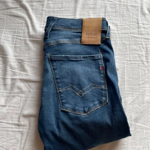 Blå jeans från Replay - Snygga blå jeans från Replay i modellen Anbass. De har en klassisk femficksdesign med dragkedja och knapp. Perfekta för en stilren look.