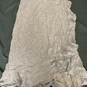 Blommig klänning från Lindex - Söt blommig klänning från Lindex i ljusblått med vita blommor. Klänningen har volangdetaljer och är perfekt för somriga dagar. Tillverkad i ett mjukt och bekvämt material. Säljer då den är för liten💕