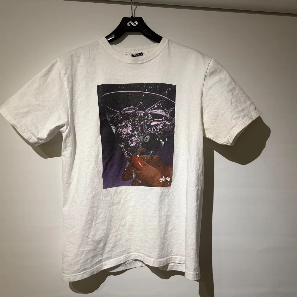 Säljer en vit t-shirt från Stussy med martini tryck. T-shirten är kortärmad och gjord av bomull och är störe i passformen. Har lite defekter på höger arm parti och små defekter över framsida annars i bra skick. Riktigt unik och svår t shirt att få tag i! Köpt för 699 säljer för 299. T-paidat.