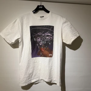 Stussy martini tee - Säljer en vit t-shirt från Stussy med martini tryck. T-shirten är kortärmad och gjord av bomull och är störe i passformen. Har lite defekter på höger arm parti och små defekter över framsida annars i bra skick. Riktigt unik och svår t shirt att få tag i! Köpt för 699 säljer för 299