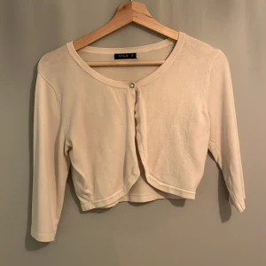 Beige kofta från Vila - Säljer en stilren beige kofta från Vila i storlek S. Koftan har trekvartsärmar och en enkel knapp framtill. Perfekt för lager-på-lager och att hålla sig varm under svalare dagar.