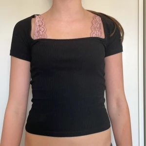 Svart ribbad topp från Gina Tricot - Snygg svart ribbad topp från Gina Tricot med korta ärmar och en öppen rygg. Perfekt för en trendig look!