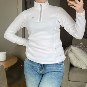 Vit långärmad tröja från Helly Hansen - OBS: fläckarna är på spegeln, inget på tröjan. Säljer en vit långärmad fleecetröja från Helly Hansen. Aldrig använd. 