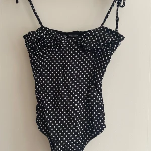 Svart prickig body från Zara - Snygg svart body med vita prickar från Zara. Den har smala axelband som knyts, man kan även ha den som linne om man viker in de. Strl s men skulle snarare säga xs.