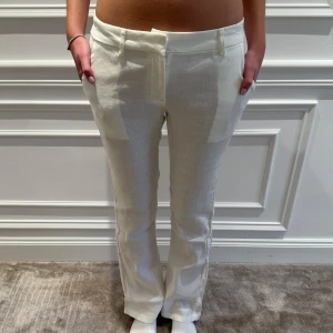 Vita linnebyxor från Nelly - Snygga vita linnebyxor från Nelly med en klassisk rak passform. Byxorna har en låg midja och stängs med dragkedja och knapp framtill. Perfekta för en stilren look. Använd 2 gånger. Byxorna har en liten fläck på högra fickan, se tredje bilden. 