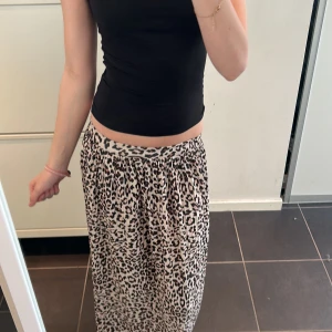 Leopardmönstrad kjol - Snygg leopardmönstrad kjol i beige och svart. Kjolen har en bekväm passform och är perfekt för att ge en trendig touch till din outfit. Den är lätt att matcha med olika toppar och accessoarer.