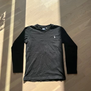 Svart långärmad tröja från Polo Ralph Lauren - Säljer en stilren svart tröja från Polo Ralph Lauren med en vit logga på bröstet. Säljer pågrund av att den är för liten. Perfekt för en avslappnad stil🔥