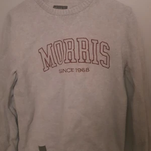 Grå tröja från Morris - Säljer en stilren grå tröja från Morris med texten 'MORRIS SINCE 1968' i rött på framsidan. Tröjan har långa ärmar och en rund halsringning. Perfekt för en avslappnad stil.