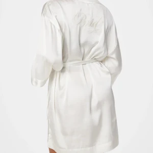 Vit sidenrock Bride - Ny med pristagg, oanvänd. Elegant vit morgonrock i siden med broderad text 'Bride' på ryggen. Den har en knytning i midjan och trekvartsärmar, perfekt för din speciella dag.