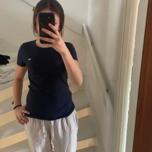Mörkblå t-shirt från Hollister - Säljer en mörkblå t-shirt från Hollister i 100% bomull. Den har en liten logga på bröstet och är kortärmad med en rund halsringning. Perfekt för en avslappnad stil.