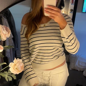 Randig offshoulder tröja - Säljer en jättesnygg randig tröja med offshoulder-design. Tröjan är vit med blåa ränder och har långa ärmar. Perfekt för sommaren!!💌passar S och XS storleksmässigt 