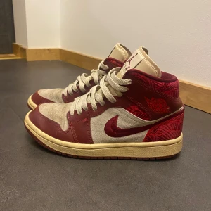 Jordan 1 - Snygga Jordans i färgen tiki leaf i en cool kombination av röd och beige. Skorna har en klassisk snörning och den ikoniska Air Jordan-loggan på plösen. Perfekta för dig som vill ha en stilren och sportig look. Dem är i bra skick men lite smutsiga men går lätt att bara tvätta av med lite vatten. Dem är köpta från Nike.