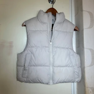 Beigevit dunväst från 157 - Säljer en stilren vit dunväst från 157 i storlek XS. Västen har en dragkedja framtill och två praktiska fickor 🤍