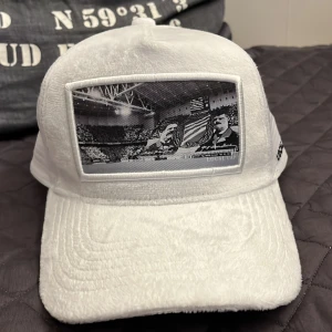 Vit keps från Local Cap - Snygg vit keps från Local Cap med ett unikt Bajen tryck på framsidan. Kepsen har en mesh-design baktill för extra ventilation och komfort. Kepsen är aldrig använd och den är riktigt skön. Perfekt till sommaren och för dig som hejar på Hammarby💚🤍