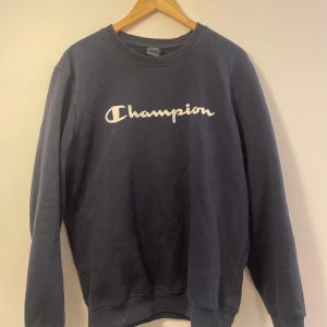 Mörkblå sweatshirt - Champion - Säljer en mörkblå sweatshirt från Champion med deras ikoniska logga i vitt på bröstet. Storlek M