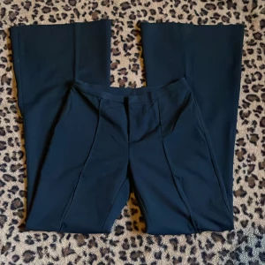 Svarta kostymbyxor - Snygga svarta kostymbyxor med låg midja och bootcut-stil. Perfekta för en stilren look. Byxorna har en elegant passform och är tillverkade i ett mjukt material som ger en bekväm känsla.