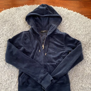 Mörkblå hoodie från Juicy Couture - Säljer en snygg mörkblå hoodie från Juicy Couture med dragkedja och broderad logga på bröstet. Hoodien har långa ärmar och en mysig huva. Jätte skön att ha i skolan också. 