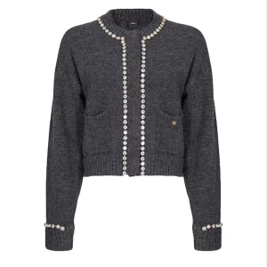 Grå kofta med glittrande stendetaljer - Grå kofta med glittrande stendetaljer – elegant och stilren. Dekorerad med gnistrande knappar längs kanterna, runt halsen och vid ärmsluten. Perfekt till både vardag och fest. Köpt i Fifth Avenue shopping mall i New York.