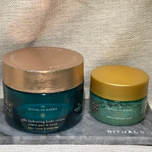 The Ritual of Karma Body Cream och Body Scrub - Säljer en uppsättning från Rituals 'The Ritual of Karma' med en 48h återfuktande body cream (stl 220ml, 50% kvar) och en mjukgörande body scrub 125gr. Krämen har doft av lotusblomma och vitt te, och kommer i en turkos burk med guldfärgat lock. Scruben har en liknande design med ett gyllene lock. Body cream är ca 50% kvar. Body scrub är ny men tyvärr har skydda folien lossnat och etiketten sitter lite löst. 