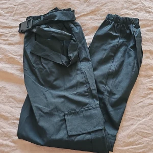 Svarta cargopants med bälte från shein - Snygga svarta cargopants i 100% polyester. Byxorna har en elastisk midja och ett praktiskt bälte. Perfekta för en avslappnad stil med flera fickor för extra förvaring.