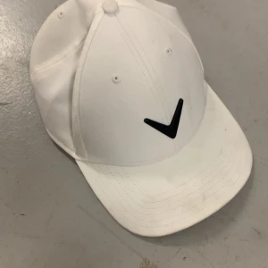 Callaway keps/ golf keps - Snygg vit keps med en stilren svart logotyp framtill. Perfekt för en sportig look eller som en stilren accessoar till vardagsoutfiten.