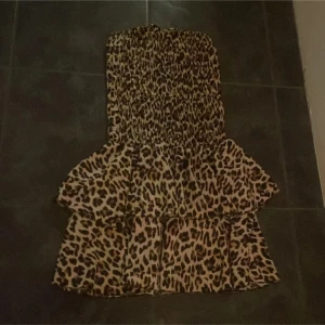 Leopardmönstrad klänning - Trendig leopardmönstrad klänning med volanger. Axelbandslös design som ger en stilren look. Perfekt för att sticka ut med ett djärvt mönster.