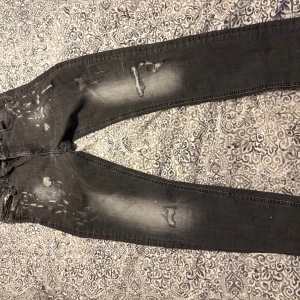 Svart gråa  jeans med slitningar - Säljer ett par grå jeans med coola slitningar och en lätt tvättad look. Perfekta för en avslappnad stil. De har en klassisk femficksdesign och knappgylf. Det är supply and demand jeans som har en liknelse med Discuard2 jeans 