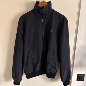 Polo Ralph Lauren jacka - Svart vatten och vindtät harrington jacka från Ralph lauren som aldrig varit använd och därför säljs. Nypriset är 2900 kr 