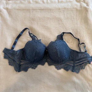 Blå spets-BH från Hunkemöller - Superfin blå BH från Hunkemöller med vacker spetsdetalj och en liten rosett framtill. Den är lite mindre i storleken. På bilden så hade jag ungefär 75D i BHstorlek. Den är använd vid väldigt få tillfällen. Nypris 599kr. 