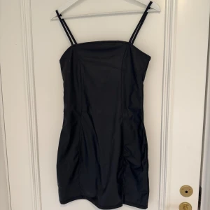 Svart klänning från H&M - Svart kort klänning i fejk läder. Använd 1 gång. 