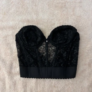Svart spetskorsett med öppen rygg - Köpt i Vintage butik i köpenhamn. Står ingen storlek men skulle uppskatta till storlek S. Ett av spännena har lossnat! 🌸
