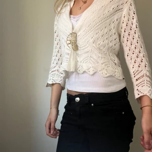 Vit stickad bolerotopp från JDY - Säljer en söt vit stickad bolerotopp från JDY. Toppen har ett fint hålmönster och trekvartsärmar. Perfekt för att lägga till en extra touch till din outfit. Passar bra över en enkel topp eller klänning.