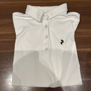 Vit Pikétröja från Peak Performance  - Säljer min vita Pikétröja från Peak Performance. En helt vanlig piké i storlek S dam men passar perfekt till jr också(12-14år) Jag har använt den som en golfpiké.