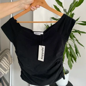Svart topp från Kappahl - Snygg svart topp från Kappahl med korta ärmar och en stilren design. Perfekt för en chic och enkel look. Toppen är tillverkad i ett mjukt material som ger en bekväm passform.
